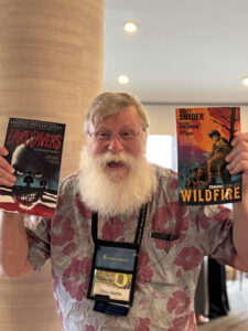 Chris Marble shares the SFF love at Book Depot set-up for our 60th Anniversary Nebula Awards Conference. (Photo Credit: Kaitrin Acuna, 2025.)