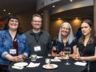 Nebula Awards Conference attendees (Gillian King-Cargile, Clint Cargile, Michelle C. Leigh, and []) share a table and a drink at our welcome reception for the weekend&#039;s events. (Photo Credit: Kaitrin Acuna, 2025.)