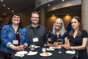 Nebula Awards Conference attendees (Gillian King-Cargile, Clint Cargile, Michelle C. Leigh, and []) share a table and a drink at our welcome reception for the weekend&#039;s events. (Photo Credit: Kaitrin Acuna, 2025.)