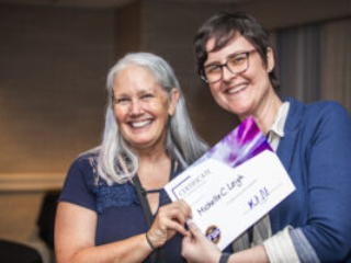 Michelle C. Leigh receives a certificate of appreciation from SFWA President Kate Ristau. (Photo Credit: Kaitrin Acuna, 2025.)
