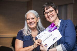 Michelle C. Leigh receives a certificate of appreciation from SFWA President Kate Ristau. (Photo Credit: Kaitrin Acuna, 2025.)