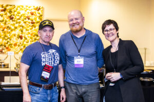 SFWA CFO Jonathan Brazee (left) and President Kate Ristau (right) celebrate Nebula Finalist Ray Nayler (center). (Photo Credit: Kaitrin Acuna, 2025.)