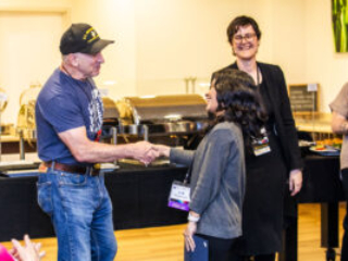 SFWA CFO Jonathan P. Brazee shakes hands with Nebula Award Winner A. W. Prihandita while SFWA President Kate Ristau smiles on. (Photo Credit: Kaitrin Acuna, 2025.)