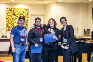 SFWA CFO Jonathan P. Brazee (left) and SFWA President (Kate Ristau) celebrate Nebula Finalists Tony Howard-Arias and Abby Howard. (Photo Credit: Kaitrin Acuna, 2025.)
