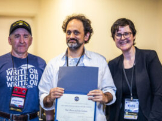 SFWA CFO Jonathan P. Brazee (left) and SFWA President (Kate Ristau) celebrate Nebula Finalist Benjamin Rosenbaum. (Photo Credit: Kaitrin Acuna, 2025.)