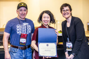 SFWA CFO Jonathan P. Brazee (left) and SFWA President (Kate Ristau) celebrate Nebula Finalist Pinki Li. (Photo Credit: Kaitrin Acuna, 2025.)