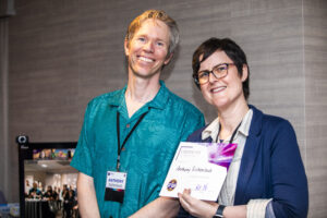 Anthony Eichenlaub receives a certificate of appreciation from SFWA President Kate Ristau. (Photo Credit: Kaitrin Acuna, 2025.)