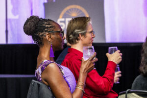 SFWA Executive Director Isis Asare and SFWA Vice-President Anthony Eichenlaub enjoy the Nebula Awards Ceremony. (Photo Credit: Kaitrin Acuna, 2025.)