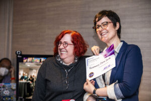 Rosemary Claire Smith receives a certificate of appreciation from SFWA President Kate Ristau. (Photo Credit: Kaitrin Acuna, 2025.)