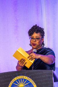 Toastmaster Erin Roberts, theatrically poised with an award-winner envelope at our 60th Anniversary Nebula Awards Ceremony. (Photo Credit: Kaitrin Acuna, 2025.)