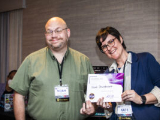 Noah Sturdevant receives a certificate of appreciation from SFWA President Kate Ristau. (Photo Credit: Kaitrin Acuna, 2025.)