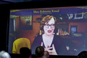 Past SFWA President Mary Robinette Kowal surprises 60th Anniversary Nebula Awards Ceremony attendees with an online cameo appearance. (Photo Credit: Kaitrin Acuna, 2025.)
