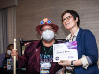 Steven D. Brewer receives a certificate of appreciation from SFWA President Kate Ristau. (Photo Credit: Kaitrin Acuna, 2025.)