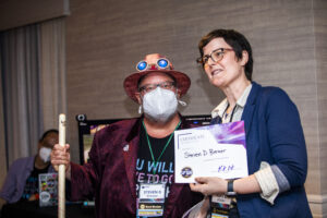 Steven D. Brewer receives a certificate of appreciation from SFWA President Kate Ristau. (Photo Credit: Kaitrin Acuna, 2025.)