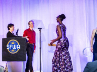 SFWA President Kate Ristau and Vice-President Anthony Eichenlaub warmly welcome Isis Asare to the stage and the organization (as our new Executive Director). (Photo Credit: Kaitrin Acuna, 2025.)