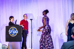 SFWA President Kate Ristau and Vice-President Anthony Eichenlaub warmly welcome Isis Asare to the stage and the organization (as our new Executive Director). (Photo Credit: Kaitrin Acuna, 2025.)