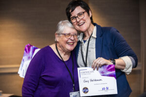 Gay Haldeman receives a certificate of appreciation from SFWA President Kate Ristau. (Photo Credit: Kaitrin Acuna, 2025.)