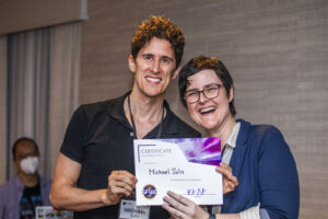 Michael Solis receives a certificate of appreciation from SFWA President Kate Ristau. (Photo Credit: Kaitrin Acuna, 2025.)