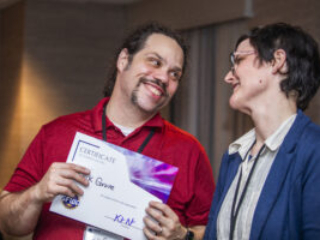 Erik Grove receives a certificate of appreciation from SFWA President Kate Ristau. (Photo Credit: Kaitrin Acuna, 2025.)