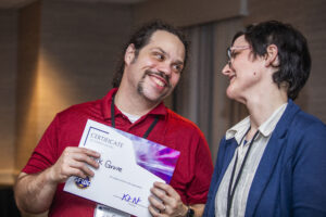 Erik Grove receives a certificate of appreciation from SFWA President Kate Ristau. (Photo Credit: Kaitrin Acuna, 2025.)