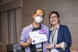 Curtis Chen receives a certificate of appreciation from SFWA President Kate Ristau. (Photo Credit: Kaitrin Acuna, 2025.)