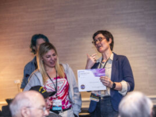 Katelyn (Kat) Brehm receives a certificate of appreciation from SFWA President Kate Ristau. (Photo Credit: Kaitrin Acuna, 2025.)