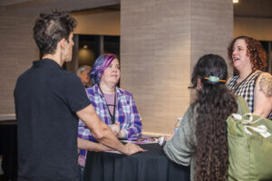 Panelists Michael Solis and Kelsey Josephson chat with other attendees during opening events at our 60th Anniversary Nebula Awards Conference. (Photo Credit: Kaitrin Acuna, 2025.)