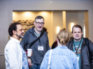Hang time! Nebula Finalist Benjamin Rosenbaum, Jason Hill from Choice of Games, and fellow attendees mingle at our 60th Anniversary Nebula Awards Conference. (Photo Credit: Kaitrin Acuna, 2025.)
