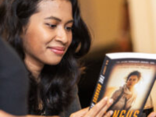 Nebula Award Winner A. W. Prihandita, enjoying the back copy of a book by another attendee.