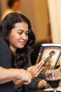Nebula Award Winner A. W. Prihandita, enjoying the back copy of a book by another attendee.