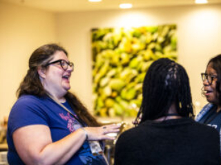 Nebula Conference attendee Katie Spina shares a moment of delight with SFWA Director-at-Large Christine Taylor-Butler (far right) and Executive Director Isis Asare (foreground). (Photo Credit: Kaitrin Acuna, 2025)