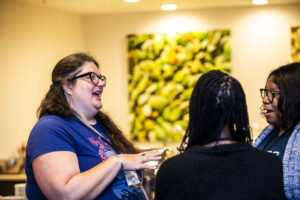 Nebula Conference attendee Katie Spina shares a moment of delight with SFWA Director-at-Large Christine Taylor-Butler (far right) and Executive Director Isis Asare (foreground). (Photo Credit: Kaitrin Acuna, 2025)